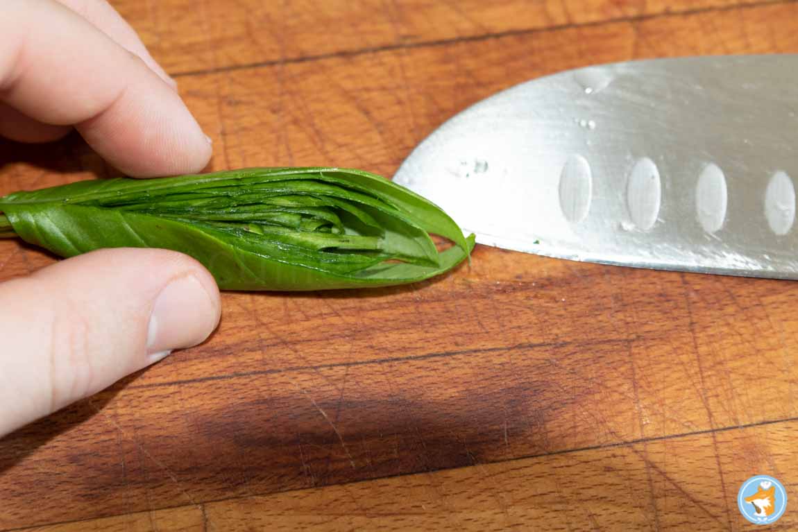 Roulez ensuite les feuilles de basilic et coupez-les en deux dans le sens de la longueur. 